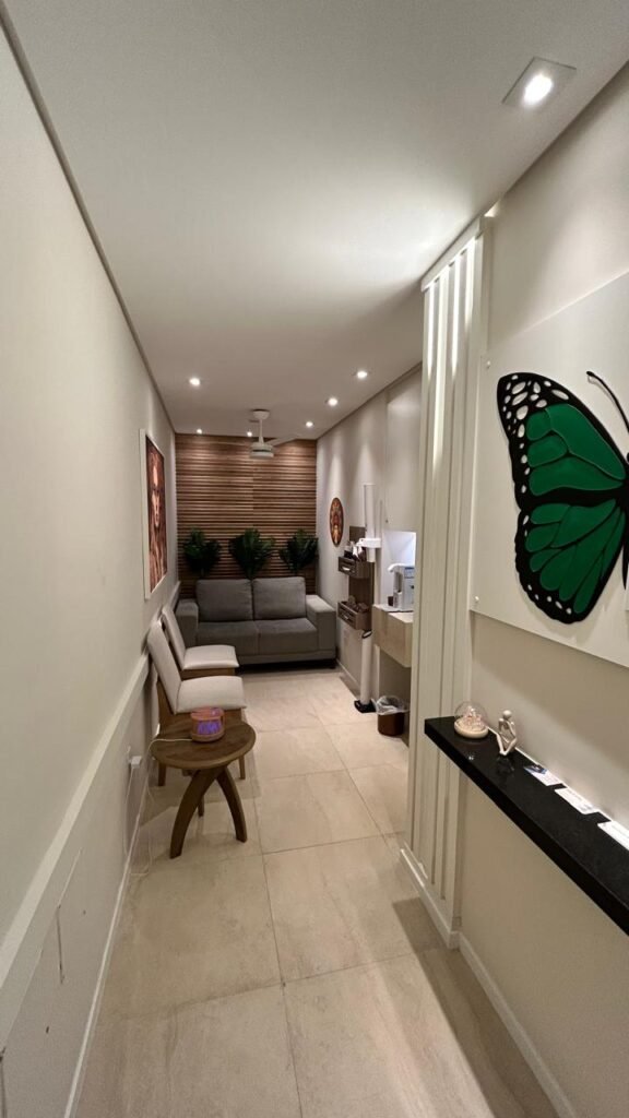 Recepção do Instituto RSI – Clínica de Psicologia em Santos Recepção premium do Instituto RSI em Santos, com sofá cinza, painel ripado de madeira, iluminação embutida e espaço de café para pacientes.